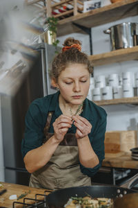 Young woman holding food while sitting on table