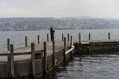 Rear view of man standing by sea against sky