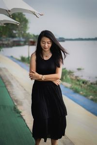 Portrait of young woman standing against sky