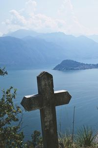 Cross in cemetery against sky