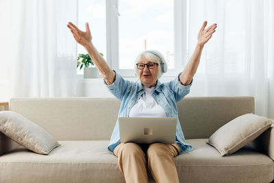 Young woman using laptop while sitting on sofa at home