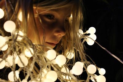 Close-up of girl holding illuminated lighting equipment in darkroom