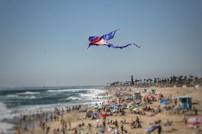 People enjoying at beach against clear blue sky