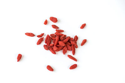 High angle view of red berries on white background