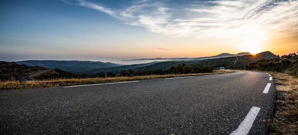 Surface level of road against sky during sunset