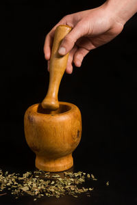 Close-up of hand holding table against black background