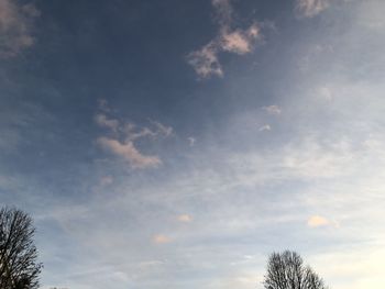 Low angle view of bare tree against cloudy sky