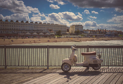 White motor scooter parked on pier against sea on sunny day