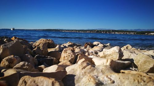 Rocks on beach against clear blue sky