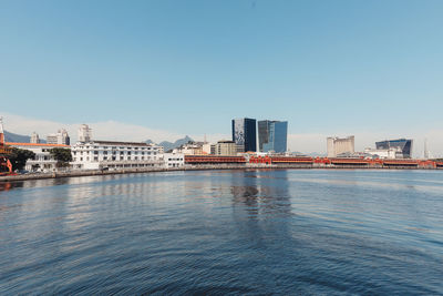 Sea by buildings against clear blue sky