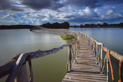 Pier on sea against cloudy sky