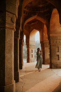 Full body of female tourist admiring arches of aged stone building located in lodi garden during vacation in india