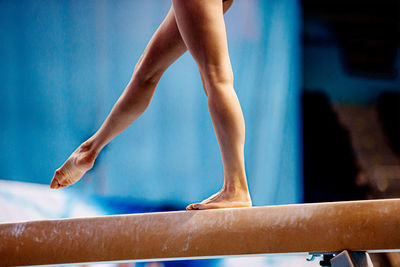 Low section of gymnast standing on wooden plank