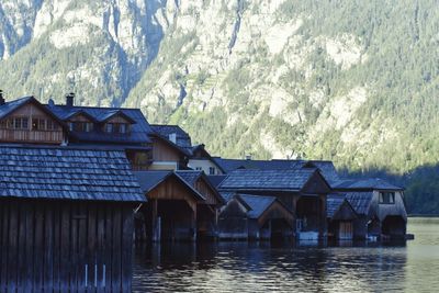 Houses by lake and buildings against mountain