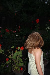 Rear view of woman standing by flowering plants