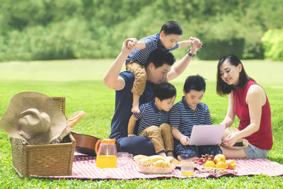 Happy family sitting on picnic blanket at public park