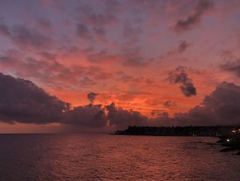 Scenic view of sea against dramatic sky during sunset