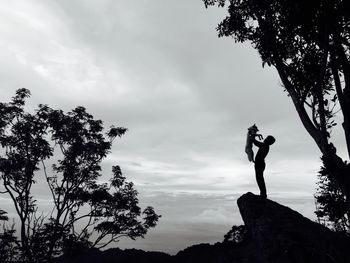 Low angle view of silhouette woman standing against sky