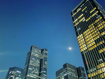 Low angle view of modern buildings against clear blue sky