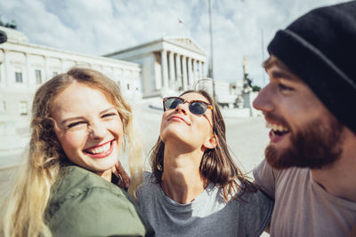 Austria, vienna, three friends having fun in front of the parliament building