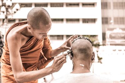 Close-up of monk shaving man head