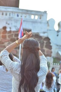 Rear view of woman with arms raised against sky