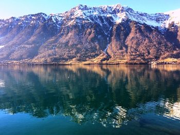 Scenic view of lake by snowcapped mountains against sky