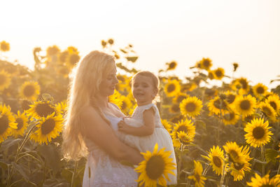 Rear view of woman and yellow flowering plants on land