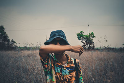Rear view of woman standing on field against sky