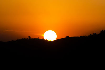 Scenic view of silhouette landscape against orange sky