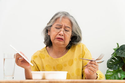 Portrait of woman sitting against wall