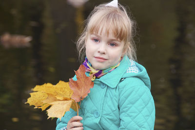 Cute girl holding autumn leaf outdoors
