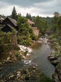 River flowing amidst buildings and trees against sky