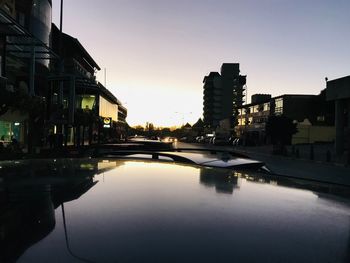 Canal amidst buildings against sky at sunset