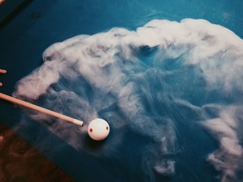 High angle view of cue ball amidst smoke on pool table