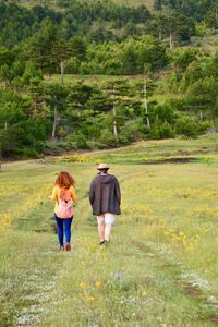 Rear view of man and woman walking on field