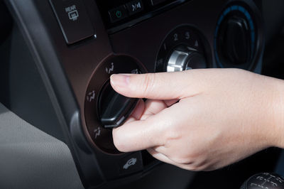 Cropped hand of woman holding knob in car