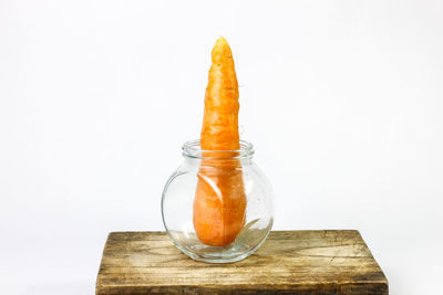 Close-up of orange fruit on table against white background