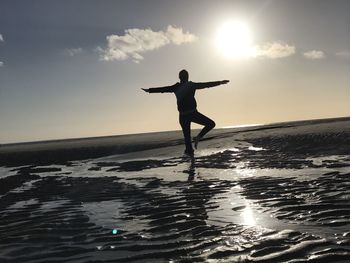 Silhouette man standing on beach against sky during sunset