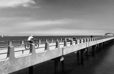 Rear view of woman perching on railing against sea