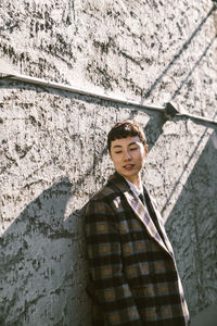 Portrait of young man standing against wall