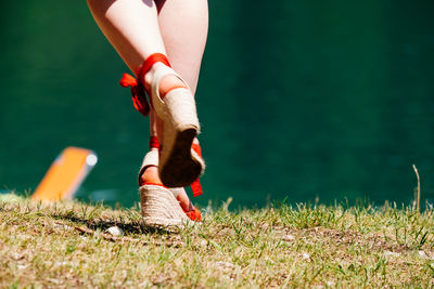 Low section of woman wearing high heels running on grassy field