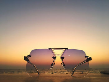 Ferris wheel on beach against clear sky during sunset
