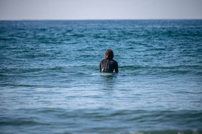 Rear view of man in sea against sky