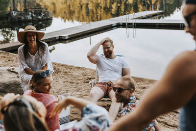 Happy friends sitting at lake