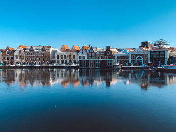 Reflection of buildings in a frozen lake against blue sky