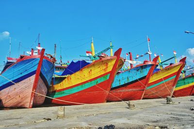 Multi colored boats moored on beach against clear blue sky