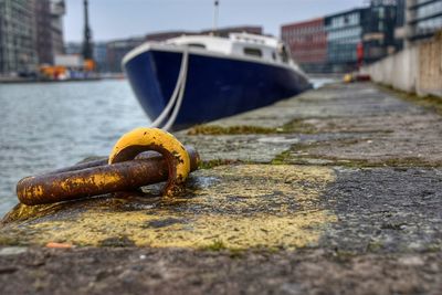 Close-up of rusty chain on boat moored at harbor against sky