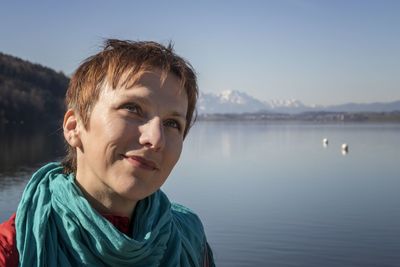 Smiling woman looking away against lake and sky