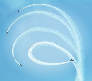 Low angle view of airplanes flying against blue sky